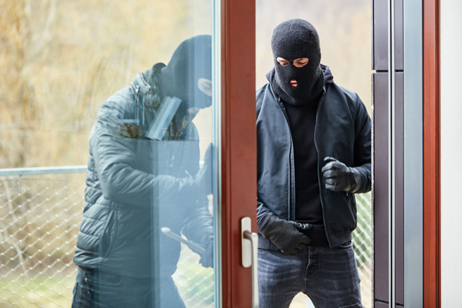 deux cambrioleurs ouvrent une porte de terrasse et regardent étonnés dans l'appartement