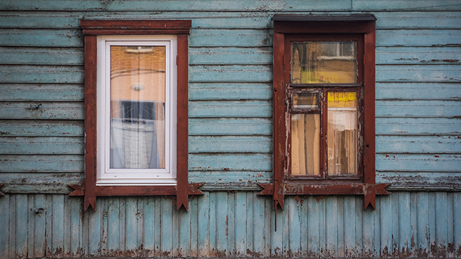Neues Kunststofffenster und Altes Holzfenster in einer Fassade aus Holz