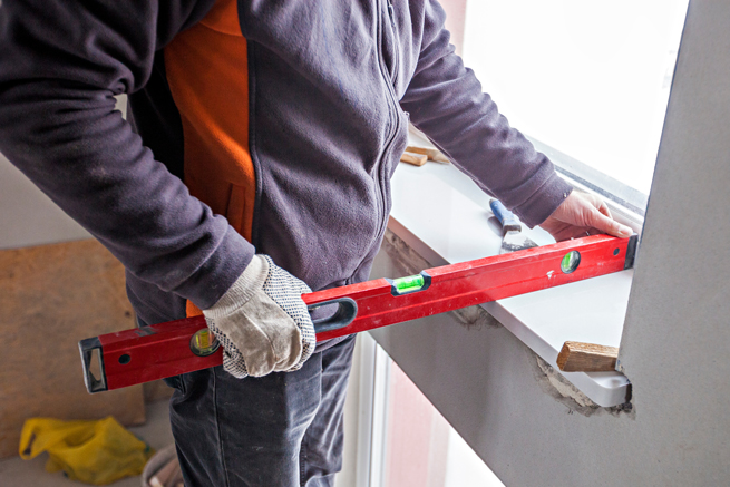 Fensterbank wird von Monteur eingebaut und richtig ausgerichtet