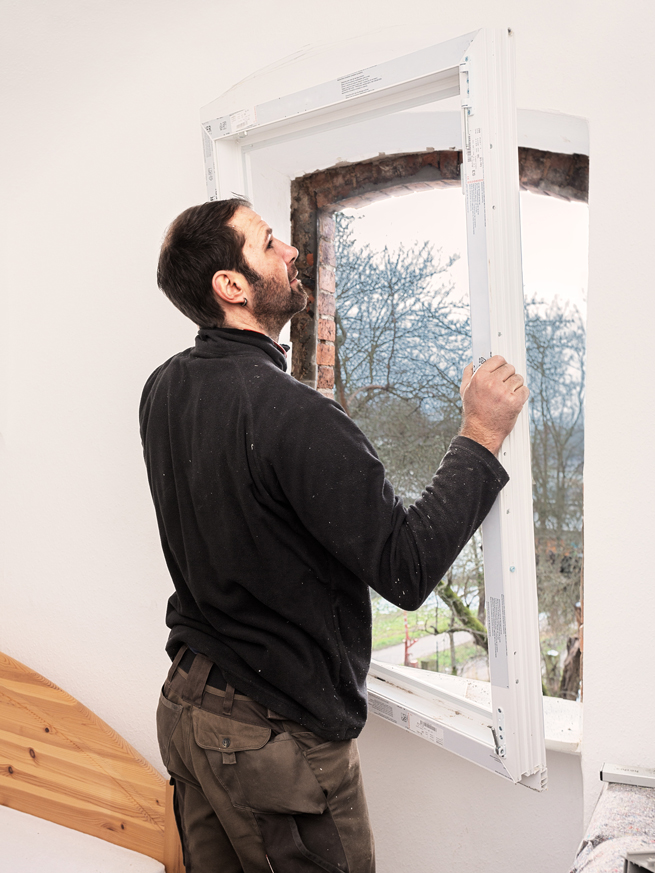 Arbeiter montiert einen Blendrahmen in eine Fensteraussparung