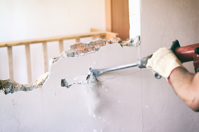 Handwerker benutzt Presslufthammer um einen Mauerdurchbruch herzustellen für eine Tür oder ein Fenster