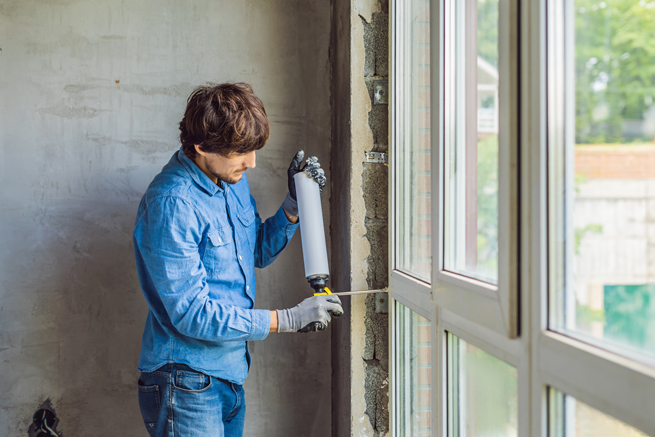 Handwerker dichtet den Wandanschluss eines Fensters mit Montageschaum ab