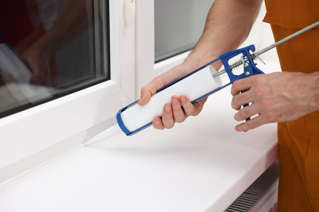 Handwerker erneuert die Silikonfuge am Fenster