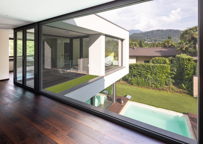 Moderne Hauskonstruktion mit viel Fensteranteil und überhängendem Stockwerk über Pool