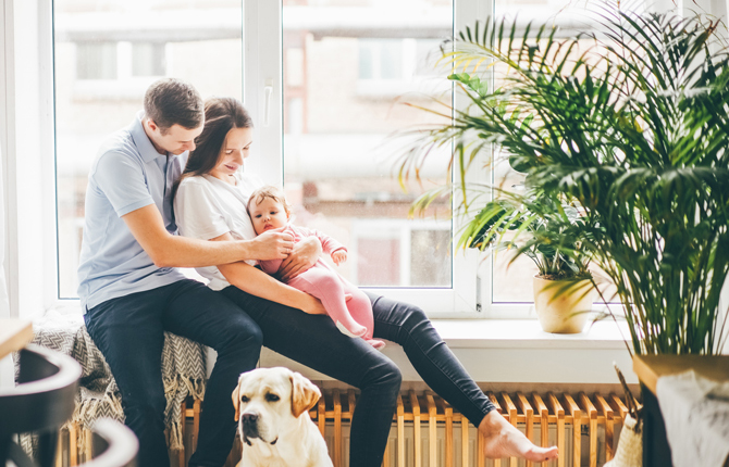 Couple avec enfant assis devant une fenêtre PVC blanche