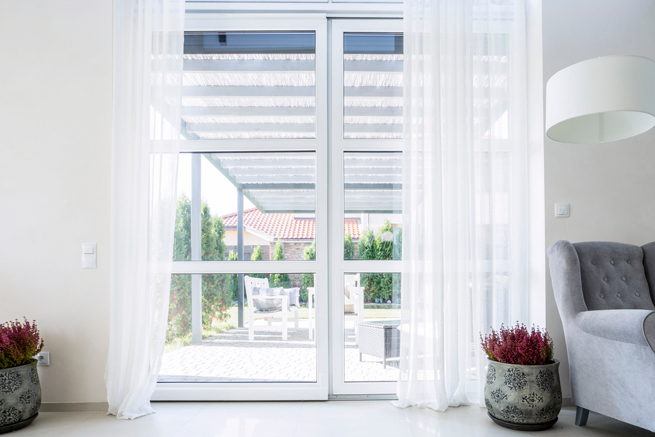 Blick durch eine Parallel-Schiebe-Kipp-Türe aus Kunststoff in den Garten