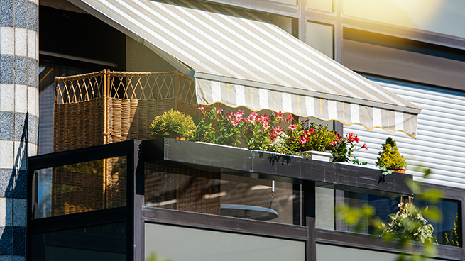 Markise über einem Wohnbalkon mit Blumen