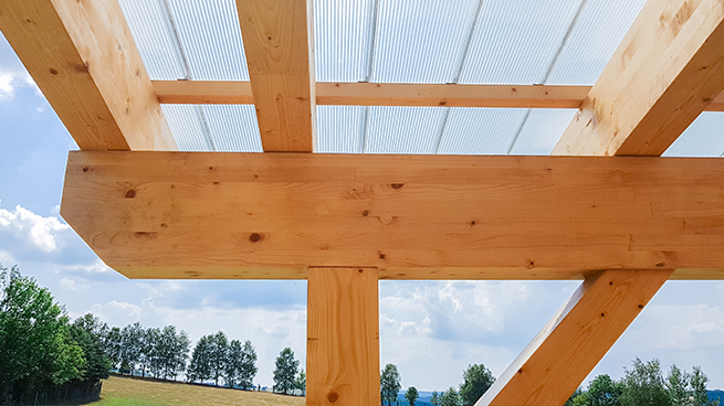 Stützbalken einer Terrassenüberdachung aus Holz mit einem Stück Dach