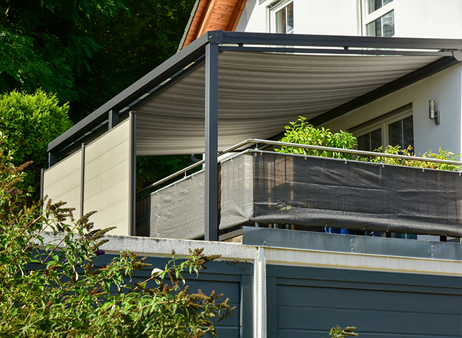 Sonnenschutz unter einem Terrassendach mit Balkonpflanzen am Haus