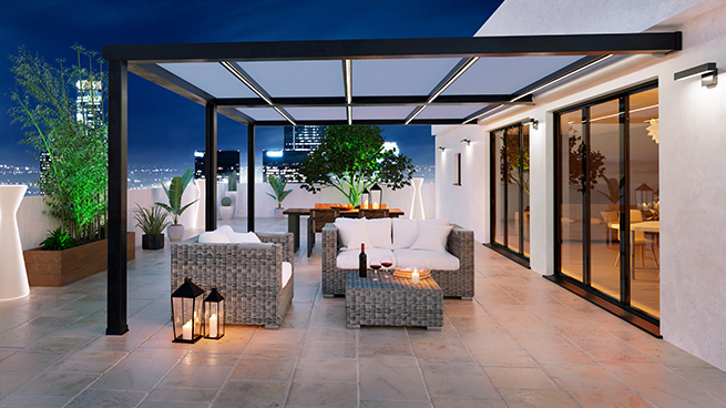 Schöne Pergola mit Gartenmöbeln und warmer Beleuchtung von Wohnraum innen