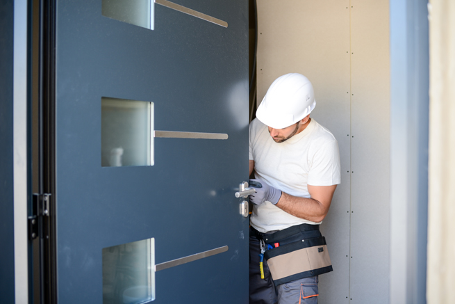 Arbeiter baut eine moderne Haustüre ein und bewundert Technik und Konstruktion