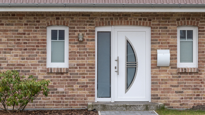 Porte d'entrée blanche avec partie latérale dans un mur de maison en briques
