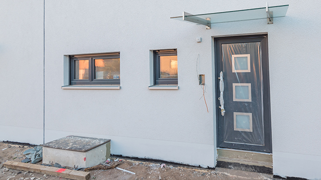 Neubau mit frischem Putz und neu eingebauter Haustüre und Fenstern