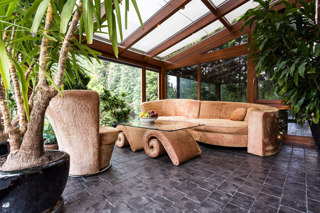 Stylisch eingerichteter Holzwintergarten mit Palmen und Extravaganten Möbeln