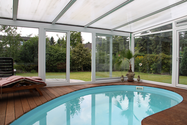 Weißer Wintergarten innen mit Pool und Liegemöbeln