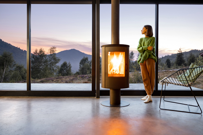 Wintergarten mit großer Glasfront und einer Frau neben einem Kamin
