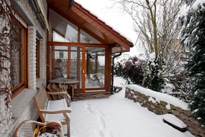 Wintergartenanbau aus Holz mit massivem Dach im Winter