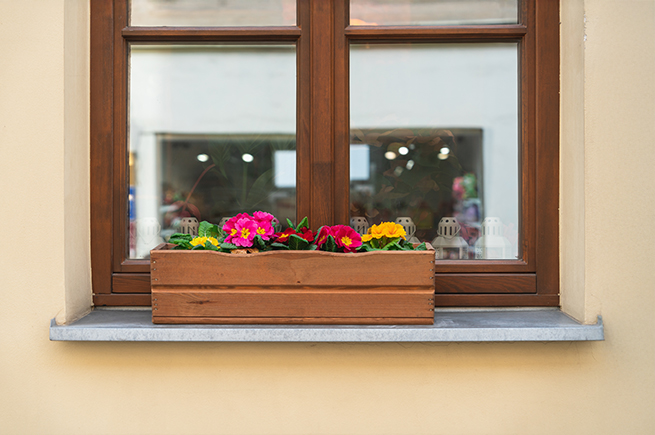 Eine Aluminium-Außenfensterbank vor einem Holzfenster mit einem Blumenkübel