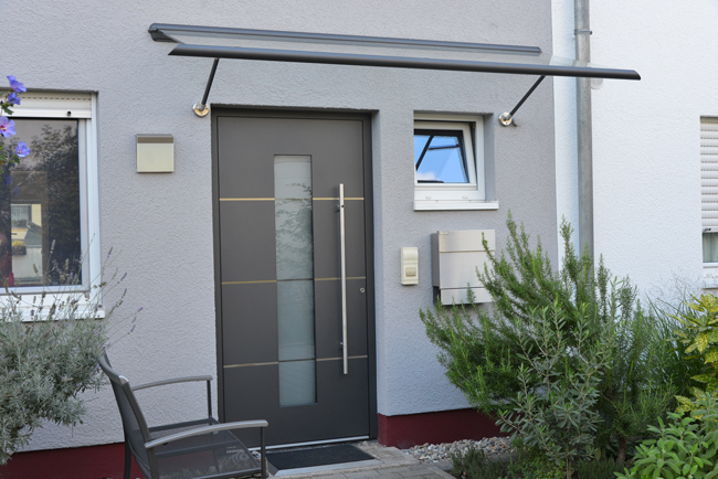 Haustür in Anthrazit mit Glaseinsatz in der Mitte in grauer Neubau-Fassade