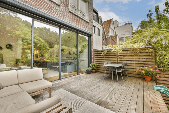 Une porte coulissante à quatre vantaux mène à une terrasse moderne