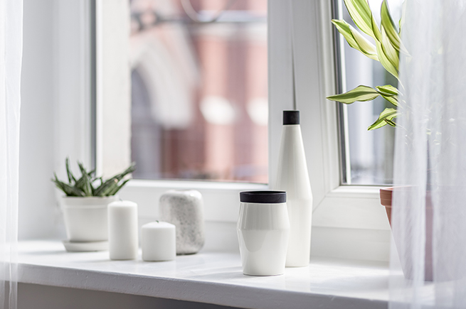 Un appui de fenêtre blanc avec des vases et des plantes devant une fenêtre blanche