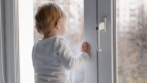 Jeune enfant se tenant à une fenêtre avec une poignée verrouillable