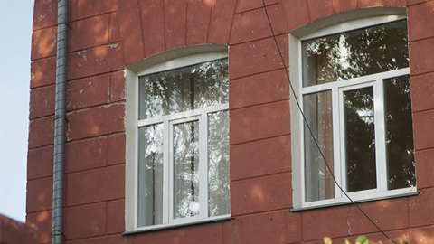 Zwei weiße Fenster mit Oberlicht in roter Hausfassade