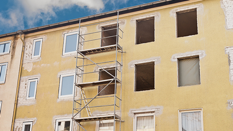 Une maison avec des fenêtres aménagées et un échafaudage de chantier devant la façade
