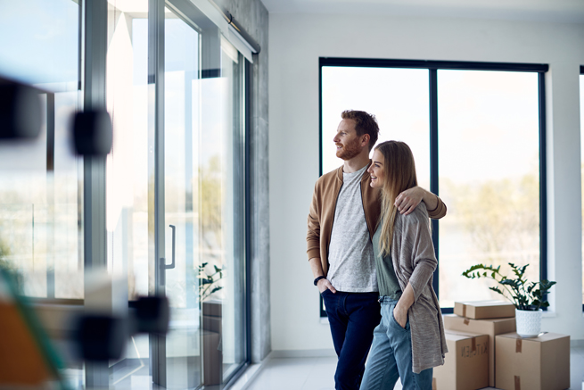 Junges Paar schaut aus den neuen Fenstern ihrer Wohnung