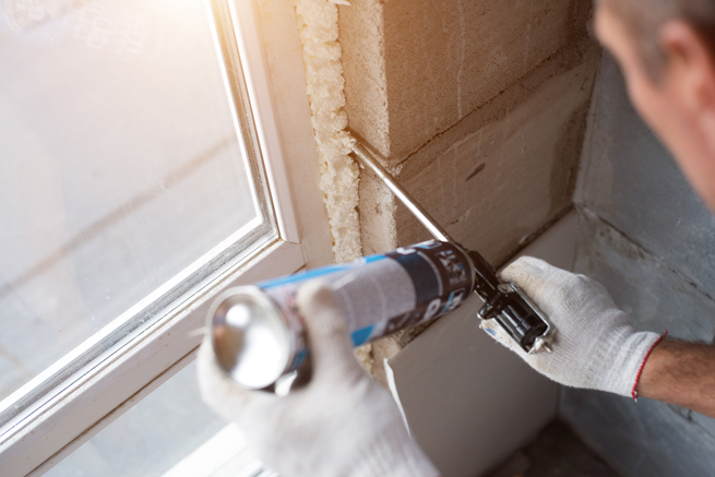 Handwerker benutzt Bauschaum zum abdichten des Fensteranschlusses