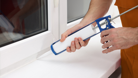 Handwerker erneuert die Silikonfuge am Fenster