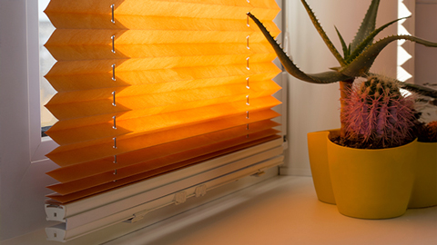 Un plissée orange comme protection solaire intérieure à la fenêtre