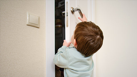 Un enfant essaie d'ouvrir une porte