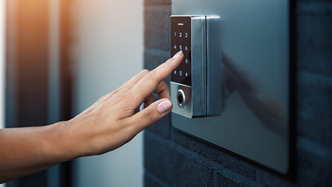 Eine Hand tippt einen Code ein an einem Codeschloss für eine Haustür