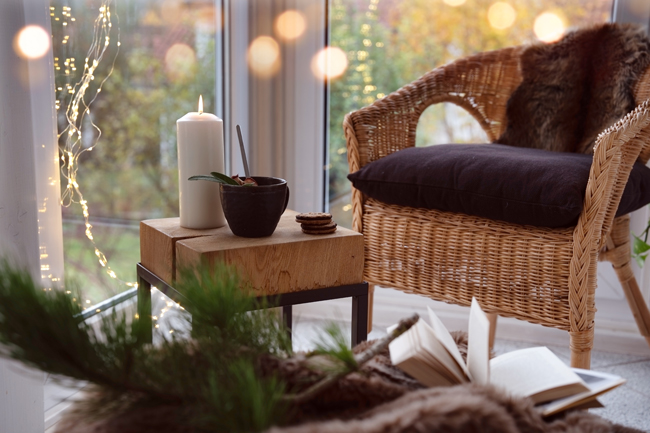 Gemütlicher Wintergarten mit Sessel und kleinem Tisch mit Kerze
