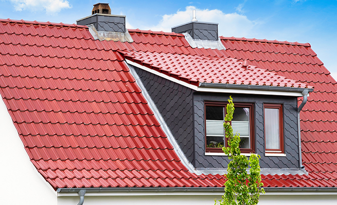 Lucarne rampante sur un nouveau toit en tuiles rouges