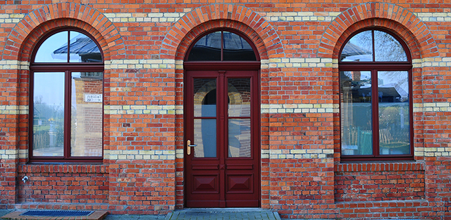 Façade classique d'une maison en briques avec fenêtres en bois cintrées et porte d'entrée en bois