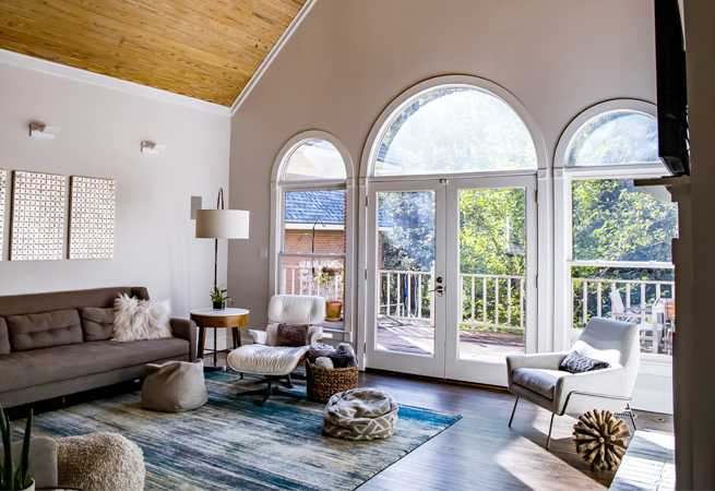 Wohnzimmer mit drei großen Rundbogenfenstern und hellem Balkon