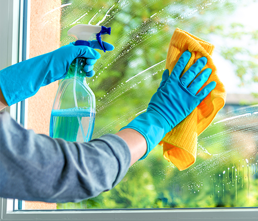 Reinigung eines Fensters mit Mikrofasertuch und Putzmittel