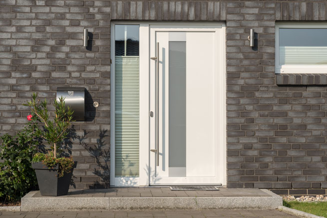 porte d’entrée blanche sur mur de briques grises