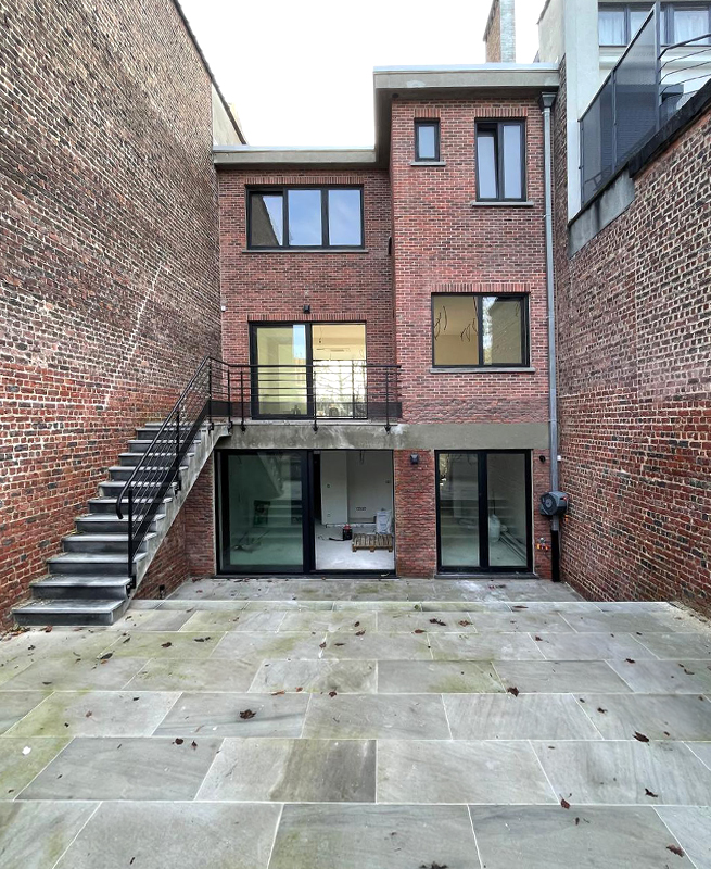Arrière de l'ancien bâtiment à Bruxelles, après le remplacement des anciennes fenêtres et portes de terrasse par de nouveaux éléments de fenêtre modernes noirs