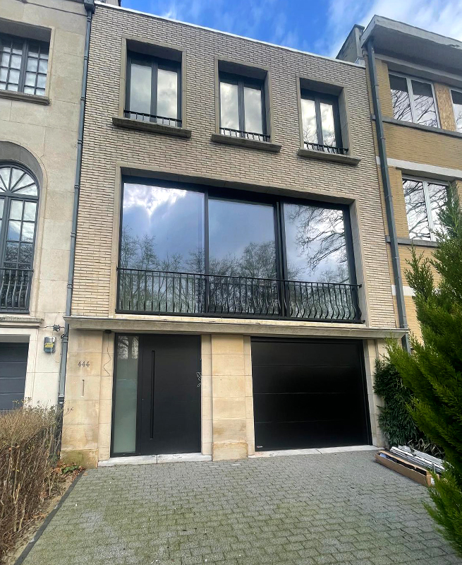 Nouvelle façade de l'ancien bâtiment à Bruxelles avec nouvelle porte d’entrée, fenêtres, façade vitrée du sol au plafond et porte de garage