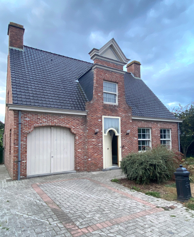 Bâtiment ancien à Grimbergen avec fenêtres blanches, ancienne porte d’entrée et ancienne porte de garage